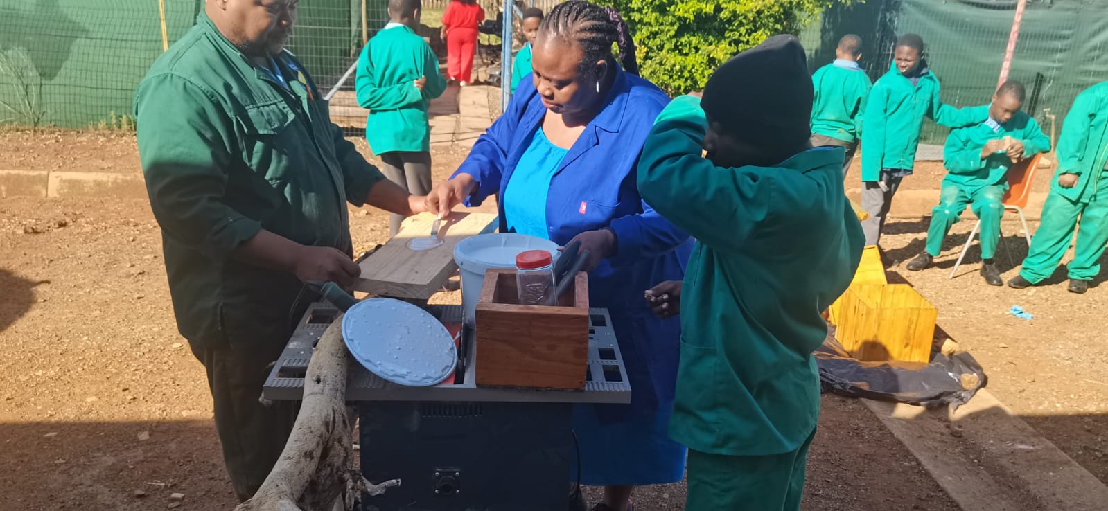 Staff and learners assembling wooden furniture outdoors