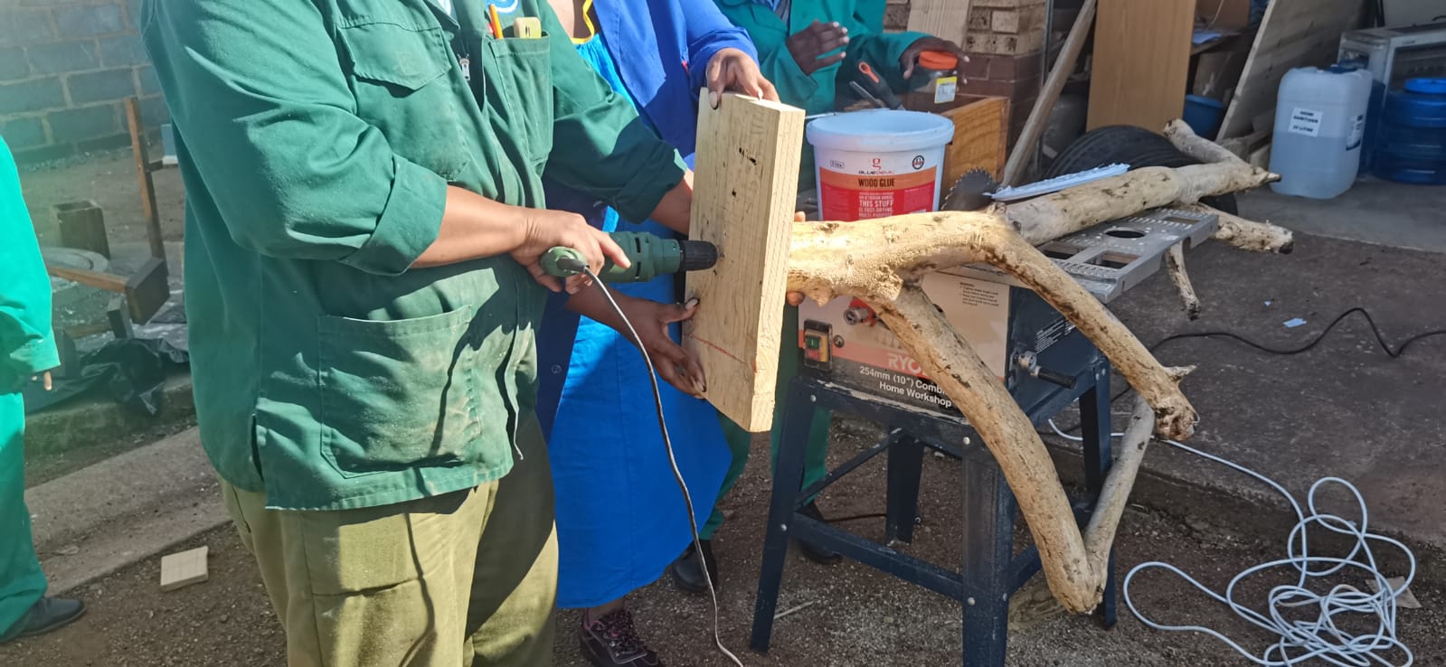 Staff member guiding a drill through a timber plank