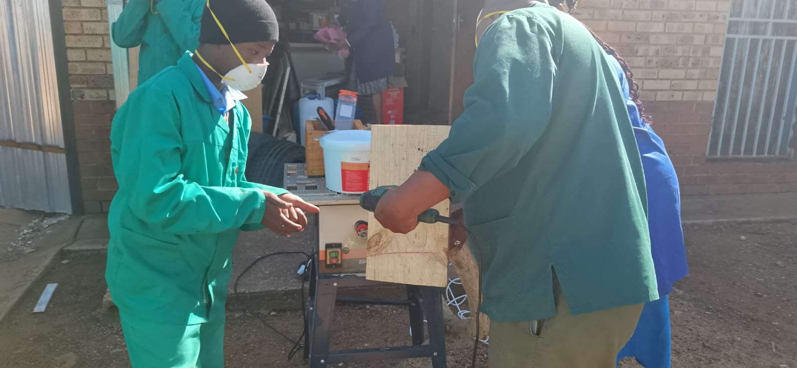 Learners and staff cutting timber with a circular saw